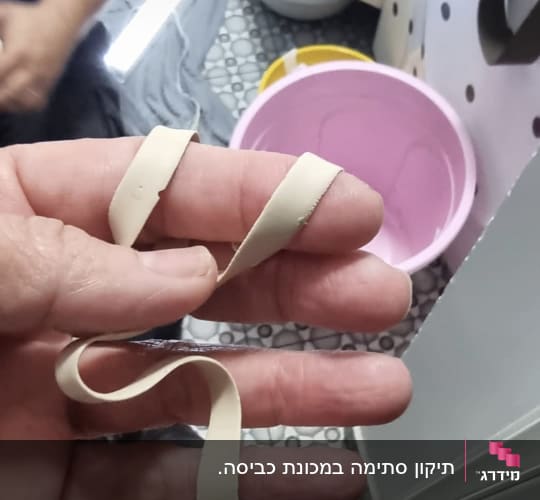 יד מחזיקה רצועת גומי ליד דלי ורוד